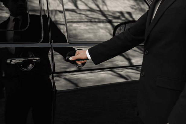 Un chauffeur aidant un couple à charger des bagages dans un véhicule familial de transport.
